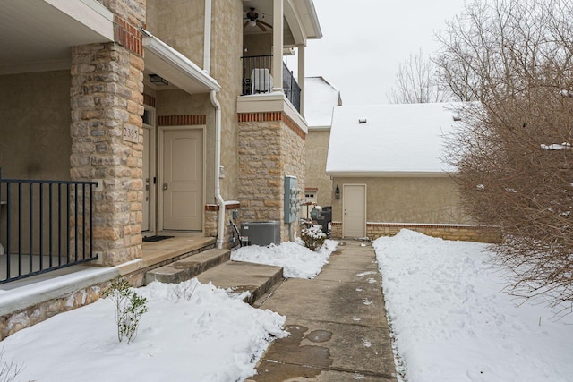 snow covered property entrance featuring a balcony, central AC unit, and ceiling fan