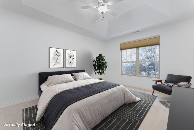 carpeted bedroom with ceiling fan and a tray ceiling