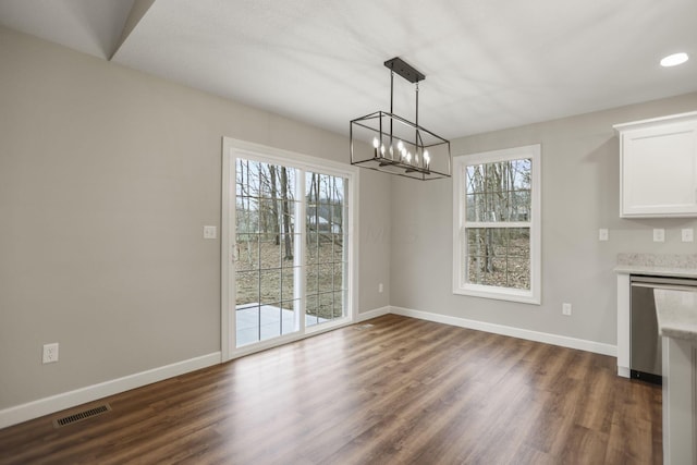 unfurnished dining area featuring dark hardwood / wood-style flooring and an inviting chandelier