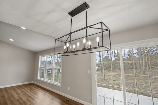 unfurnished dining area with hardwood / wood-style floors and a chandelier