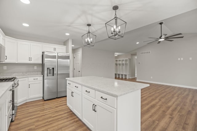 kitchen featuring white cabinets, ceiling fan with notable chandelier, appliances with stainless steel finishes, decorative light fixtures, and a kitchen island