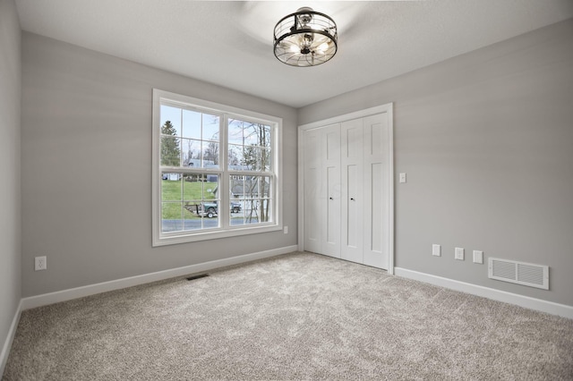 unfurnished bedroom featuring light colored carpet and a closet