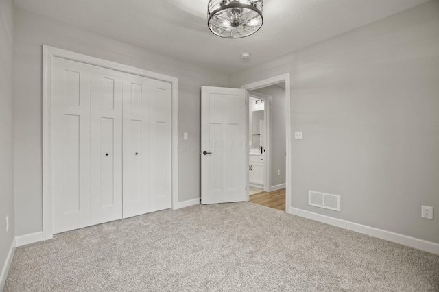 unfurnished bedroom with a closet and light colored carpet