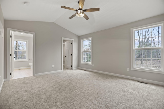 unfurnished bedroom with connected bathroom, ceiling fan, light colored carpet, and vaulted ceiling