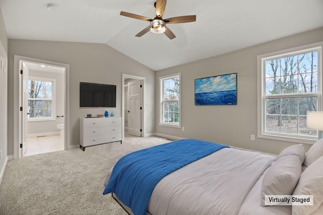 bedroom featuring ensuite bath, ceiling fan, light colored carpet, and vaulted ceiling