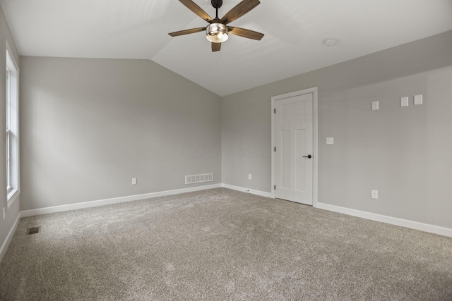 carpeted spare room with ceiling fan, a healthy amount of sunlight, and lofted ceiling