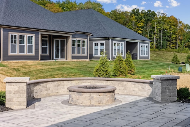 rear view of property with a fire pit, a patio, and a lawn