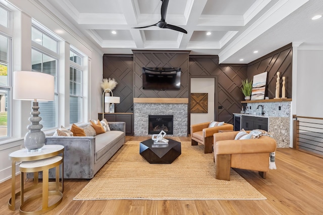 living room featuring hardwood / wood-style flooring, a stone fireplace, ceiling fan, and coffered ceiling