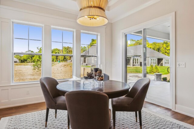 dining space featuring wood-type flooring, plenty of natural light, and crown molding