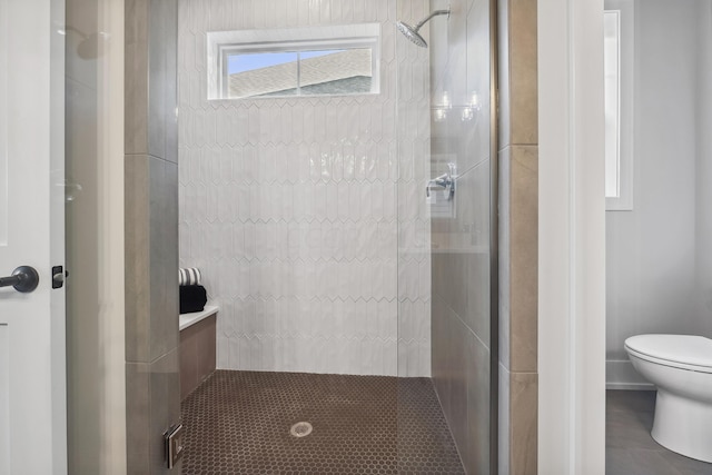 bathroom featuring tiled shower and toilet