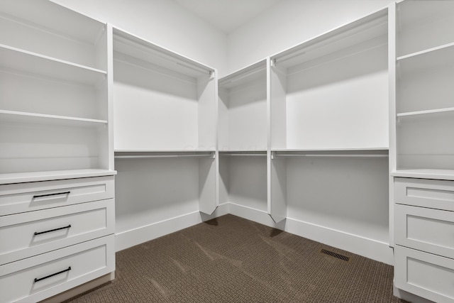 walk in closet featuring dark carpet