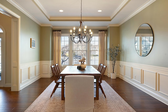 dining space featuring a raised ceiling, ornamental molding, dark wood-type flooring, and an inviting chandelier