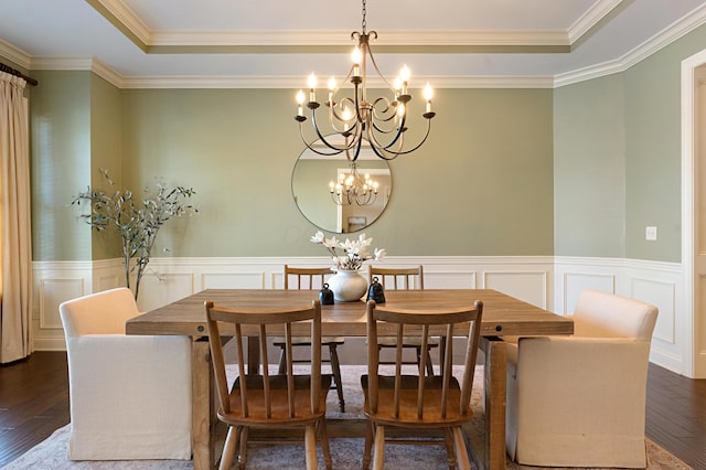 dining space with dark wood-type flooring, a chandelier, and a raised ceiling