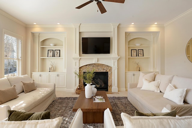 living room featuring a fireplace, carpet floors, ornamental molding, ceiling fan, and built in shelves