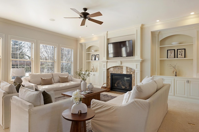 living room with crown molding, light carpet, built in features, ceiling fan, and a fireplace