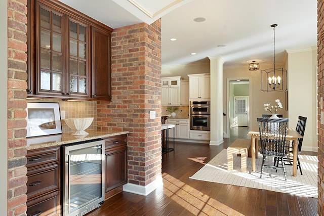 kitchen featuring crown molding, dark wood-type flooring, hanging light fixtures, wine cooler, and decorative backsplash