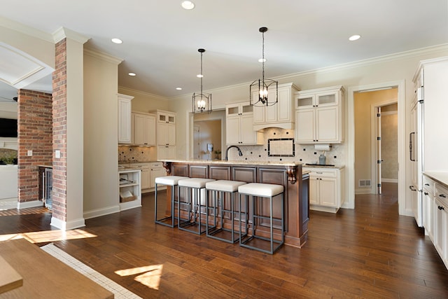 kitchen with a breakfast bar, sink, a center island with sink, dark hardwood / wood-style flooring, and pendant lighting