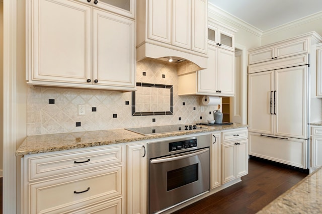 kitchen with light stone counters, stainless steel oven, black electric stovetop, and paneled fridge