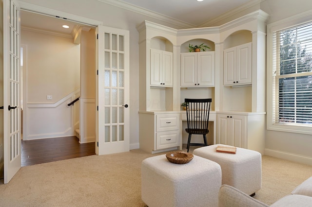 sitting room with crown molding, built in desk, french doors, and carpet flooring