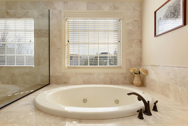 bathroom with plenty of natural light and a relaxing tiled tub