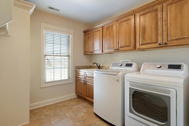 clothes washing area with cabinets, washing machine and dryer, and sink