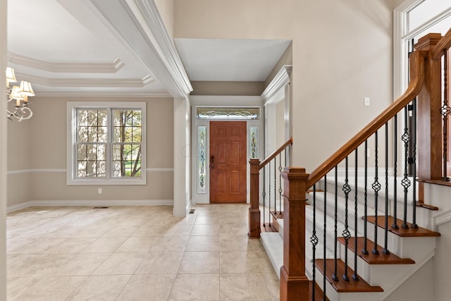 foyer entrance featuring a notable chandelier, light tile patterned flooring, a raised ceiling, and crown molding