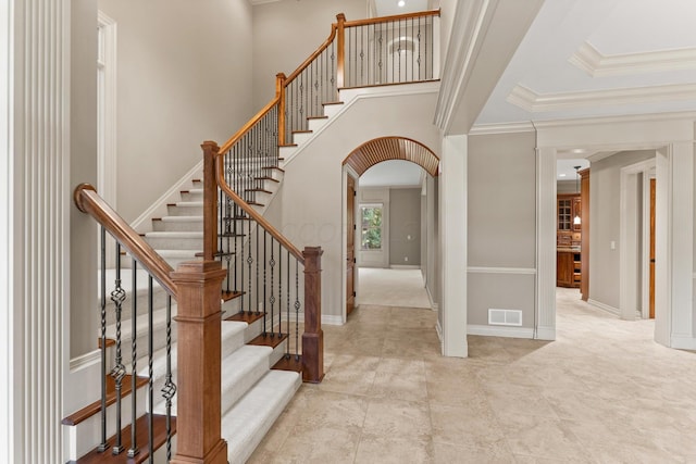 stairway with a high ceiling and crown molding