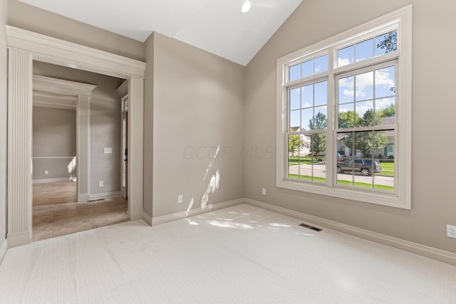 carpeted spare room with vaulted ceiling