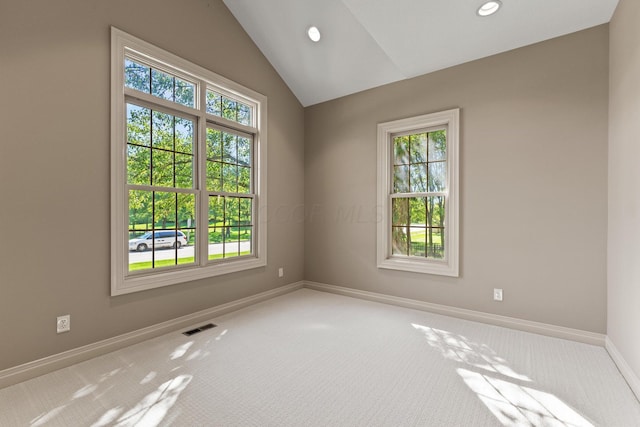 carpeted spare room with vaulted ceiling