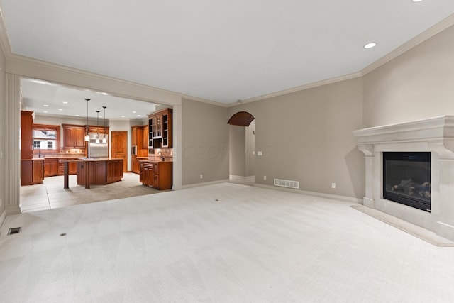 unfurnished living room featuring crown molding, a high end fireplace, and light colored carpet