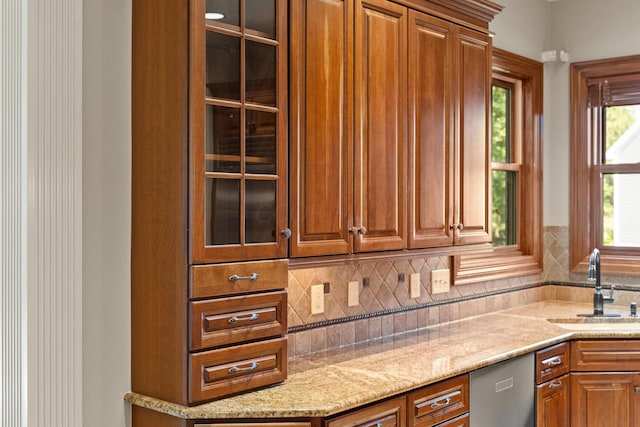 kitchen with decorative backsplash, light stone countertops, sink, and stainless steel dishwasher