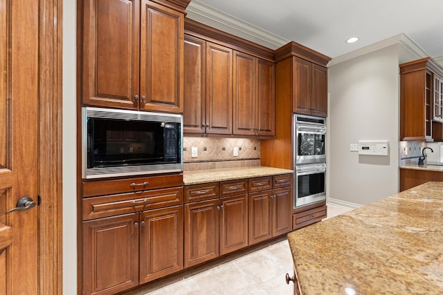 kitchen featuring ornamental molding, light stone countertops, double oven, tasteful backsplash, and black microwave