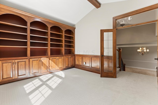 carpeted empty room with vaulted ceiling with beams, french doors, and a chandelier