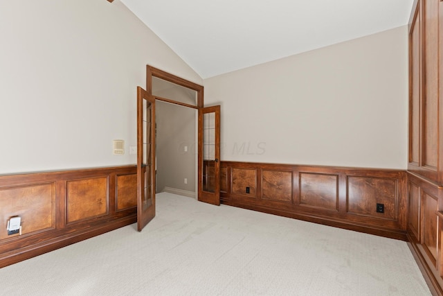 carpeted spare room with french doors and vaulted ceiling