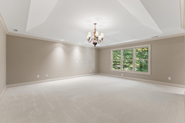 carpeted spare room with a chandelier, a tray ceiling, and crown molding