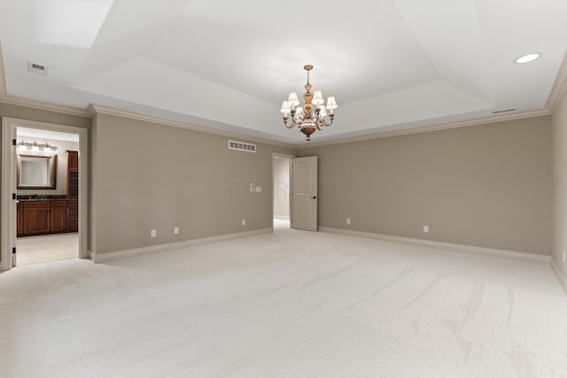 empty room featuring a notable chandelier, light colored carpet, crown molding, and a tray ceiling