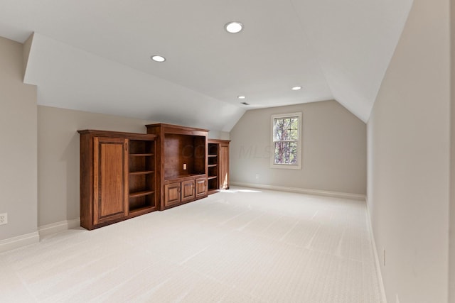 additional living space featuring light colored carpet and vaulted ceiling