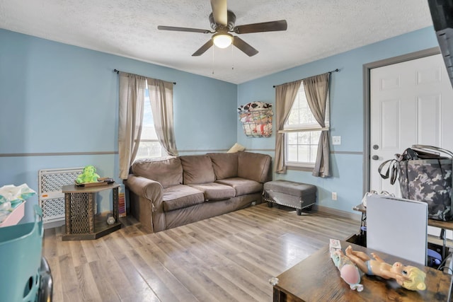 living room with ceiling fan, light hardwood / wood-style floors, and a textured ceiling