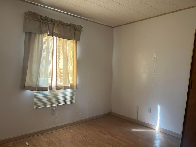 spare room with hardwood / wood-style flooring, ornamental molding, and a healthy amount of sunlight