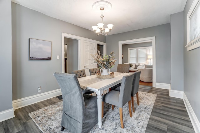 dining room with dark wood-type flooring and a chandelier