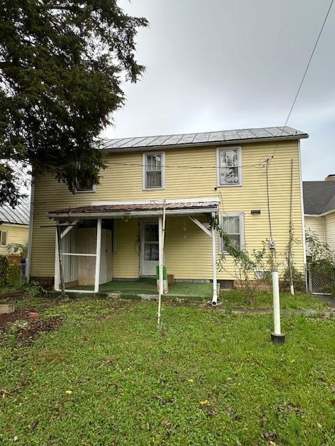 rear view of property featuring a lawn