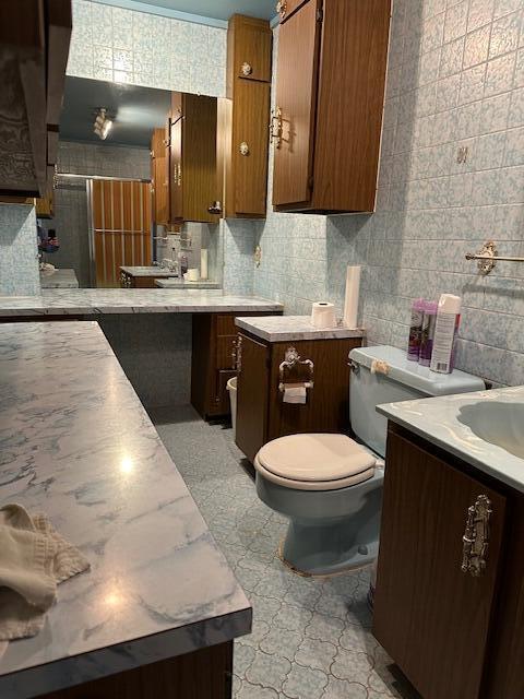 bathroom featuring tasteful backsplash, sink, tile walls, and toilet