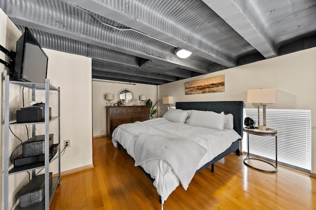 bedroom featuring beamed ceiling and hardwood / wood-style floors