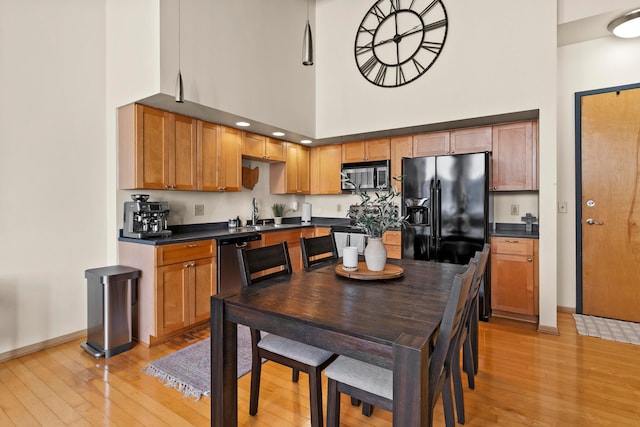 kitchen featuring stainless steel appliances, a towering ceiling, sink, and light hardwood / wood-style floors