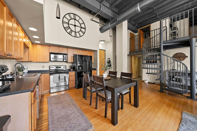 kitchen featuring stainless steel appliances, a high ceiling, sink, and light hardwood / wood-style floors