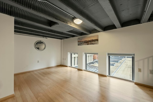 spare room featuring light hardwood / wood-style flooring and beamed ceiling