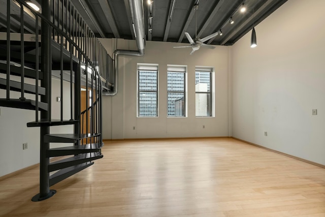 basement featuring track lighting, ceiling fan, and light hardwood / wood-style flooring