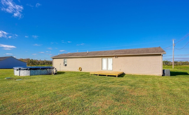 back of property with a lawn, a pool side deck, and central AC