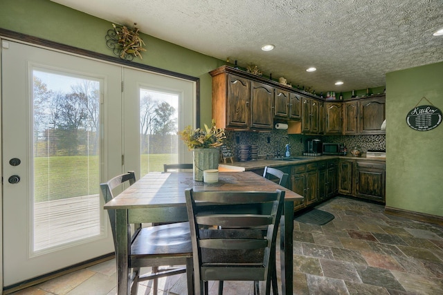 kitchen featuring dark brown cabinets, a textured ceiling, tasteful backsplash, and sink