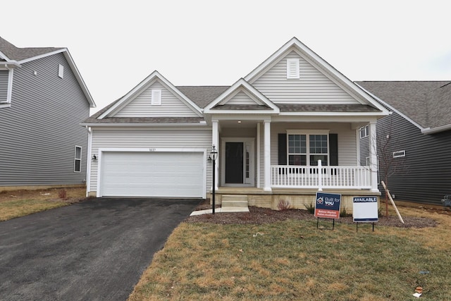 view of front of home featuring a garage, a porch, and a front yard